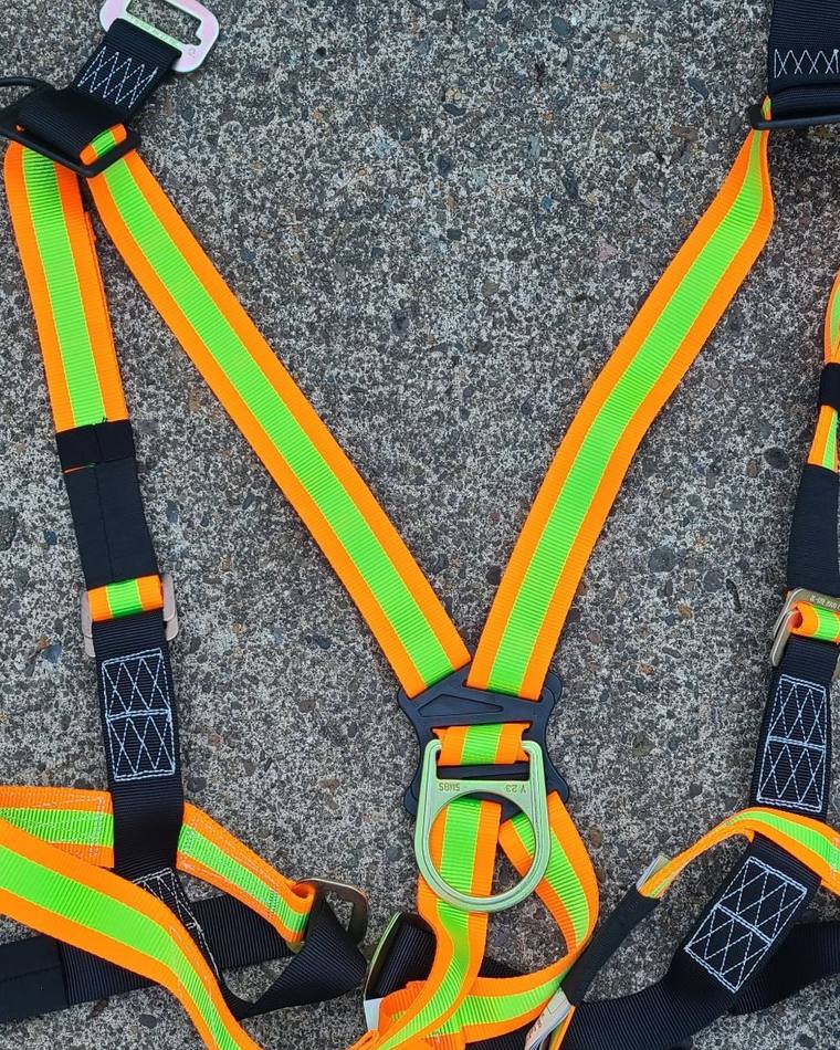 Harness laid flat on the ground, rear D-ring centered between the shoulder straps